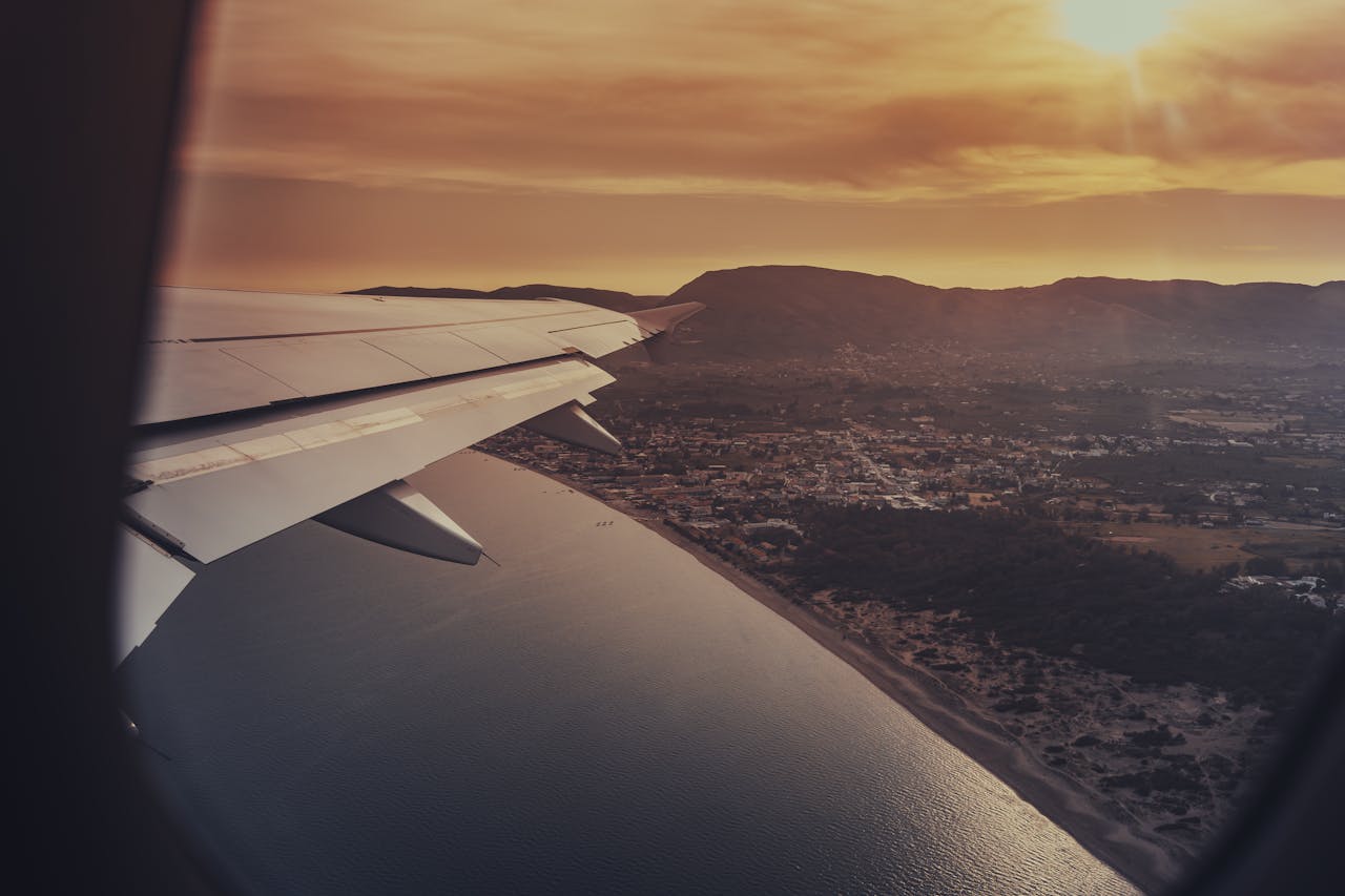 creative-03 Scenic sunset view of coastline and ocean from airplane window, capturing travel essence.