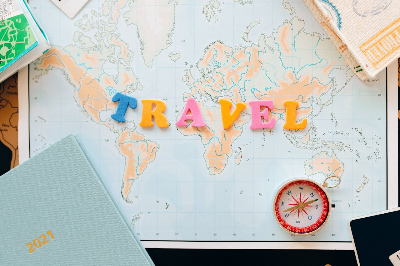 brand-02 Flat lay of a map with colorful letters "TRAVEL" and a compass for planning adventures.
