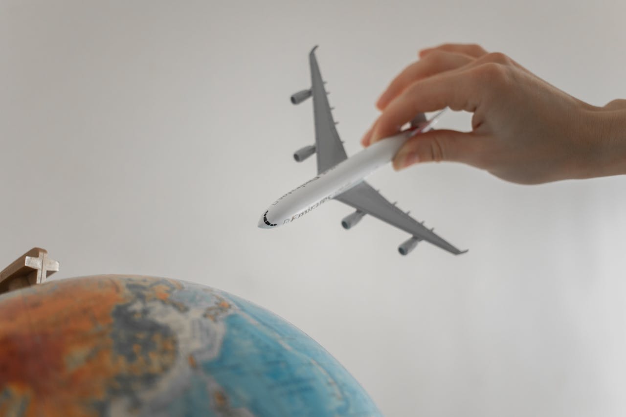 brand-01 A hand holds a toy airplane above a globe, symbolizing travel and exploration.